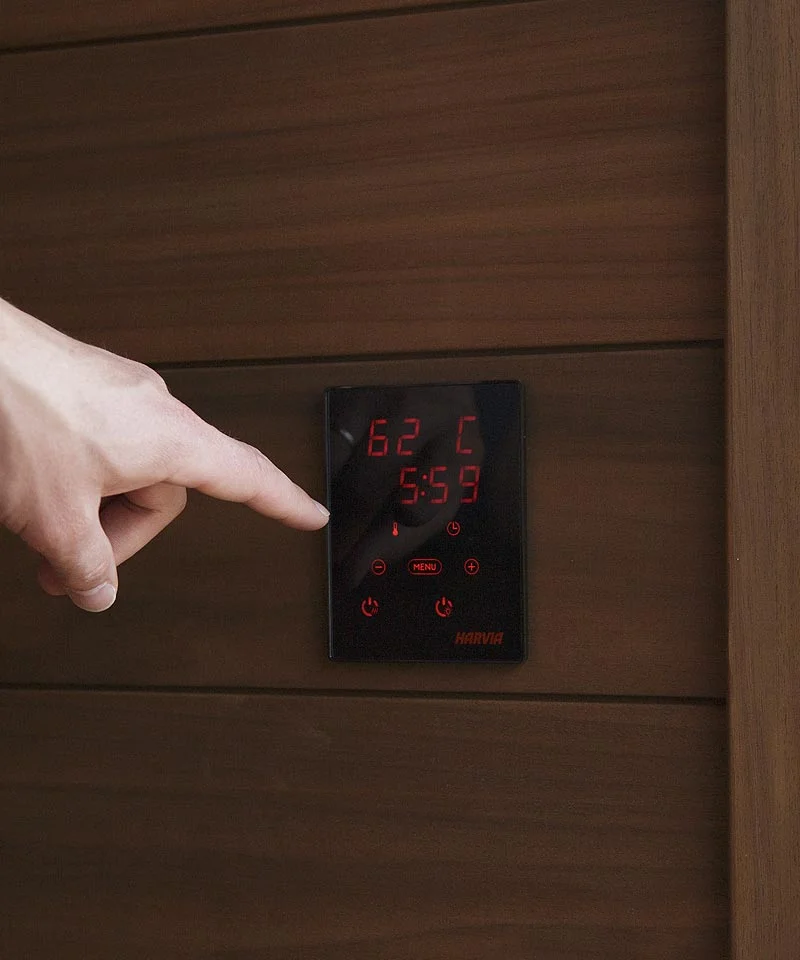 Finger touching the Harvia Xenio Wi-Fi control unit.