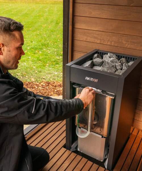 Man opens the water tank on Harvia Virta Combi sauna heater