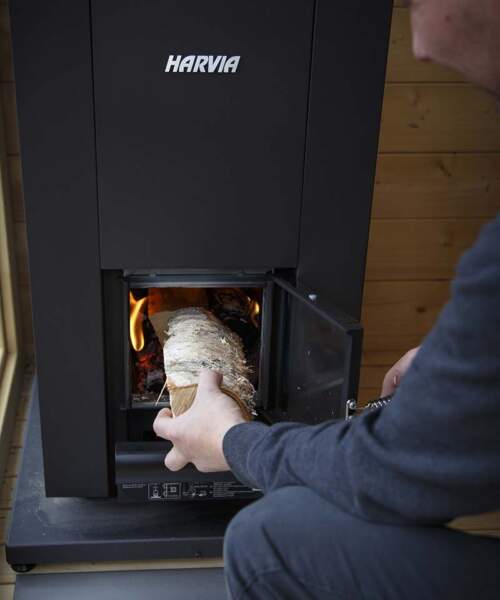 Man loads the Harvia Linear with wood