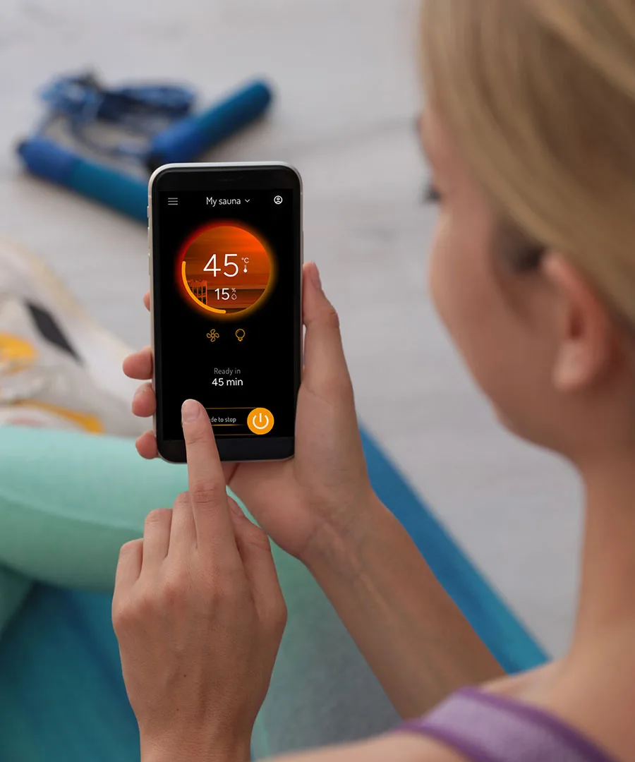 Woman controlling the Harvia Fenix remotely using the MyHarvia Phone App